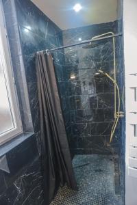 La salle de bains est pourvue d'une douche et d'un mur en marbre noir. dans l'établissement Le moderne 100 mètres de la gare parking gratuit, à Douai