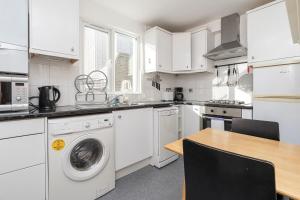 a kitchen with white appliances and a wooden table at Adorable 1 bed flat in West Brompton, sleeps 4 in London