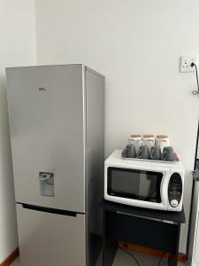 a microwave sitting on a table next to a refrigerator at MELJAA STAR Guesthouse in Cape Town