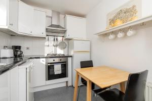 uma cozinha com armários brancos e uma mesa de madeira em Adorable 1 bed flat in West Brompton, sleeps 4 em Londres