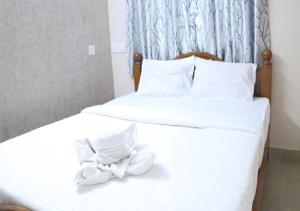 Pradee Queen Resorts في Tiruvallūr: سريرين بشرشف ابيض وقوس عليهم