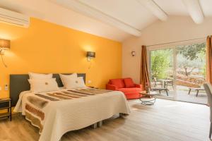 a bedroom with a large bed and a red chair at Logis Hôtel Restaurant Le Pradinas in Anduze