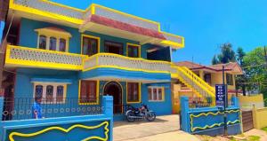 a blue and yellow house with a motorcycle parked in front at Long Wood Hills Cottage in Ooty