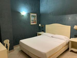 una camera con un letto bianco e una parete blu di Hotel Serena a Napoli