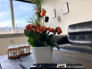 um vaso de flores sobre uma mesa ao lado de um controle remoto em Privat, skandinavisk og moderne lejlighed - med gratis parkering em Randers