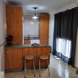 uma cozinha com armários de madeira e um balcão com dois bancos em Apartamento Cruces em El Puerto de Santa Maria