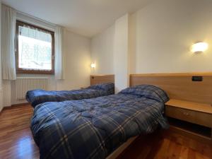 a bedroom with two beds and a window at 081 Trilocale Baldino, Pinzolo in Pinzolo