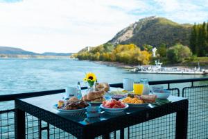 una mesa con comida en el balcón con vistas al agua en Aquamarina Hotel Visegrád en Visegrád