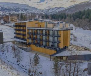 un gran edificio amarillo con nieve en el suelo en Didveli gallery bakuriani Room A102, en Bakuriani