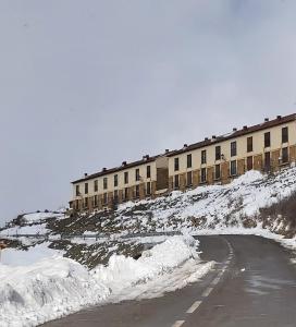 un edificio en una colina cubierta de nieve con una carretera en Casa Majo Valdelinares VUTE-23-002 en Valdelinares