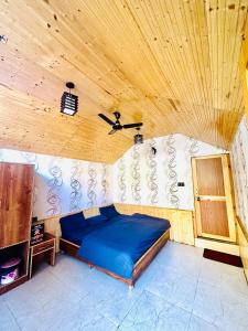 a bedroom with a blue bed in a wooden ceiling at The Aisling House in Kasol