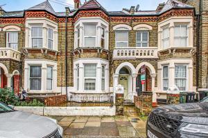 a large brick house with cars parked in front of it at The Brixton Apartment in London