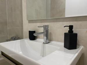een wastafel in de badkamer met een kraan en een zeepdispenser bij UpNorth Home in Boekarest