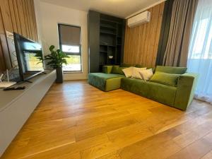 a living room with a green couch and a television at UpNorth Home in Bucharest