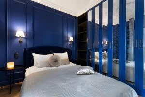 Elite Apartments Grano Residence في غدانسك: غرفة نوم بجدران زرقاء وسرير بمخدات بيضاء
