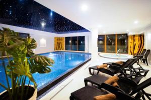 - une piscine dans une maison avec des chaises et une baignoire dans l'établissement Ultra All Inclusive Apartament w Amber Park Spa, à Niechorze