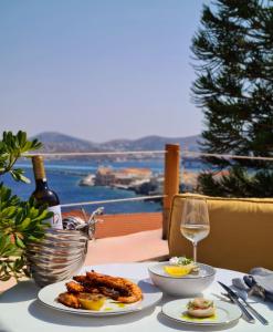 a table with two plates of food and a glass of wine at Aristide Hotel - Small Luxury Hotels of the World in Ermoupoli