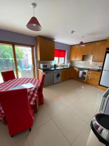 una cocina con mesa y sillas rojas, mesa y mesa. en Beach Close Lodge en Kinsale