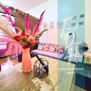 um quarto com um sofá e um vaso de flores em Tropical Home at SMDC Air Residences Makati em Manila