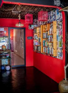 um quarto com uma parede vermelha com livros em House of Lion Hostel em Pantai Cenang