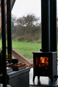 una estufa en un porche junto a una ventana en Wilder Retreats - A Frame Cabins en Haverfordwest