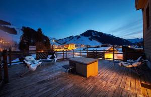 a deck with chairs and a table and a mountain at Hotel Glemmtalerhof in Saalbach-Hinterglemm