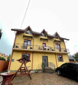a yellow house with a black car parked in front of it at Вілла Львів in Skhidnitsa