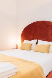 - un grand lit avec une tête de lit en bois et 2 oreillers dans l'établissement ORM Padrão Apartment, à Porto