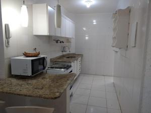una cucina con armadi bianchi e un forno a microonde su un bancone di Maitinga SESC Bertioga a Bertioga