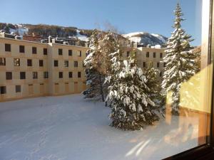 un grupo de árboles en la nieve frente a un edificio en Studio PRALOUP 4 couchages Sapinière 126 en Pra-Loup