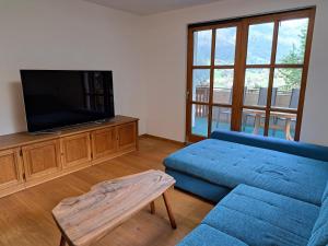 a living room with a blue couch and a tv at Ferienwohnung Irene in Galgenul