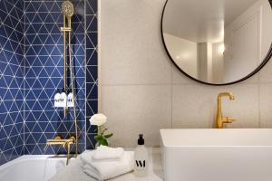 uma casa de banho com uma banheira, um lavatório e um espelho. em Artemisia Montmartre em Paris