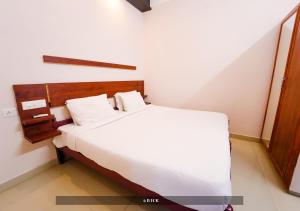 a bedroom with a large white bed in a room at Prime Casadel Rooms And Apartments in Kakkanad