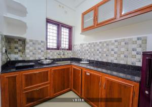 a kitchen with wooden cabinets and black counter tops at Prime Casadel Rooms And Apartments in Kakkanad +54 photos