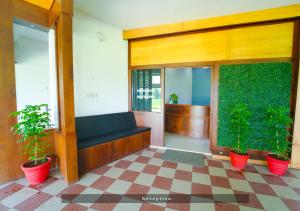 a lobby with a bench and two plants in pots at Prime Casadel Rooms And Apartments in Kakkanad