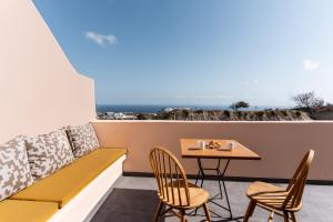 a balcony with a bench and a table and chairs at Perla Nera Suites in Fira