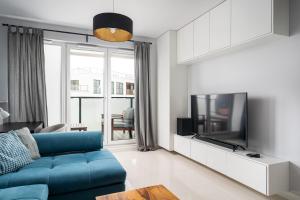 a living room with a blue couch and a tv at Bluszczańska Blue Modern Apartment in Warsaw