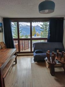 a living room with a couch and a large window at Super Sauze charmant studio en bas des pistes in Enchastrayes