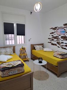 two beds in a room with yellow sheets and a table at Residence Rahma 