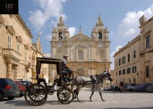 a man in a horse drawn carriage in front of a building at Historical Mdina Gem, Lux HOME with Rooftop Pool by 360 Estates in Mdina