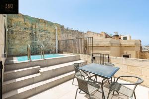 een tafel en stoelen op een balkon met een zwembad bij Historical Mdina Gem, Lux HOME with Rooftop Pool by 360 Estates in Mdina