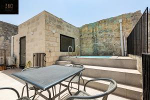 eine Terrasse mit einem Tisch und Stühlen sowie einem Pool in der Unterkunft Historical Mdina Gem, Lux HOME with Rooftop Pool by 360 Estates in Mdina