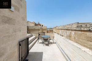 uma varanda com mesas e cadeiras numa parede em Historical Mdina Gem, Lux HOME with Rooftop Pool by 360 Estates em Mdina