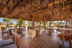 a restaurant with tables and chairs and a straw roof at Ananea More Meni Kos ex More Meni Beach in Tigaki