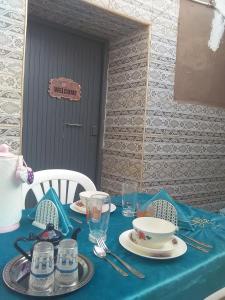 a table with a blue table cloth with plates and glasses at Grotte de pêcheurs RITAJ, Aglou in Tiznit