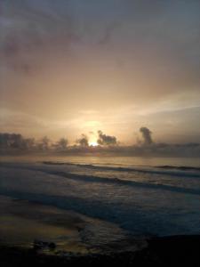 um pôr do sol na praia com o oceano em Grotte de pêcheurs RITAJ, Aglou em Tiznit