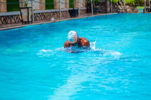 a man swimming in a pool in a swimming pool at La Grande Hotel in Kampala