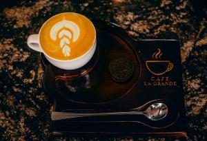 a cup of coffee sitting on a black plate at La Grande Hotel in Kampala