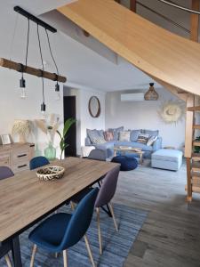 ein Wohnzimmer mit einem Holztisch und blauen Stühlen in der Unterkunft Chez Iris in Jebsheim