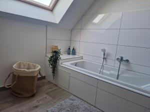 ein weißes Bad mit einer Badewanne und einem Fenster in der Unterkunft Chez Iris in Jebsheim
